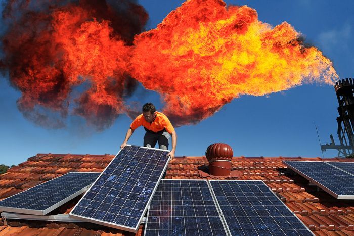 Gorgon Gas project and solar power emissions A worker installing rooftop solar panels with a industrial chimney venting a big flame behind.