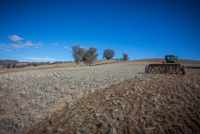 Farmer sowing in dry paddock A tractor ploughing a dry paddock