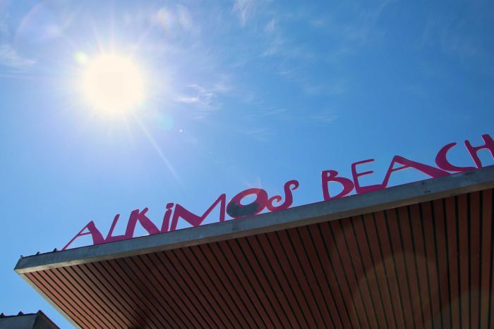 Sign at Alkimos Beach An Alkimos Beach sign on a building with the sun shining in the background.