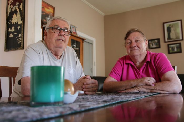 The Williams at their table An older couple sit at a dining room table inside their home, chatting.