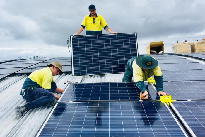 Solar panel installers on a school roof Solar panel installers on a school roof